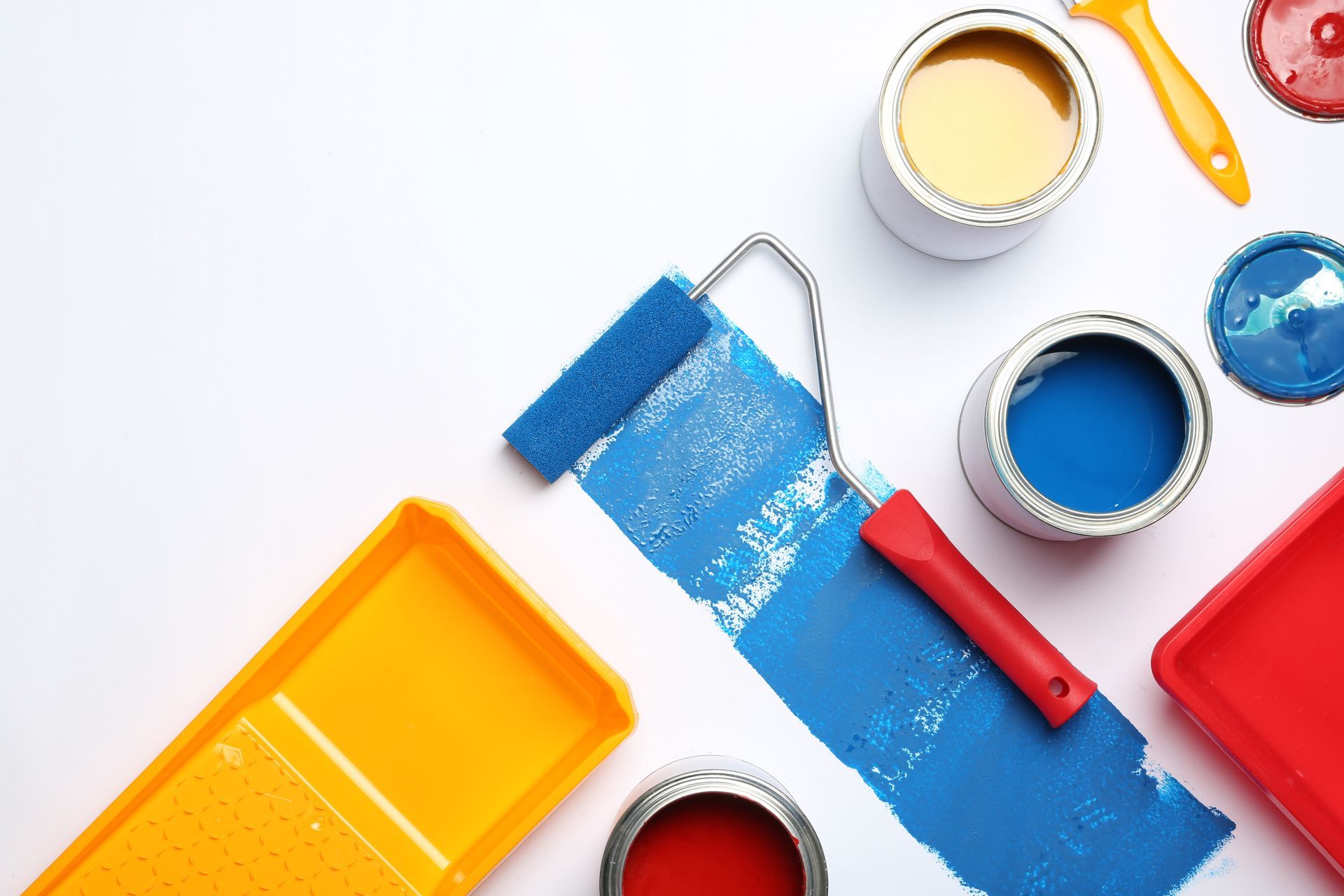 a paint roller , trays , and cans of paint on a white surface .