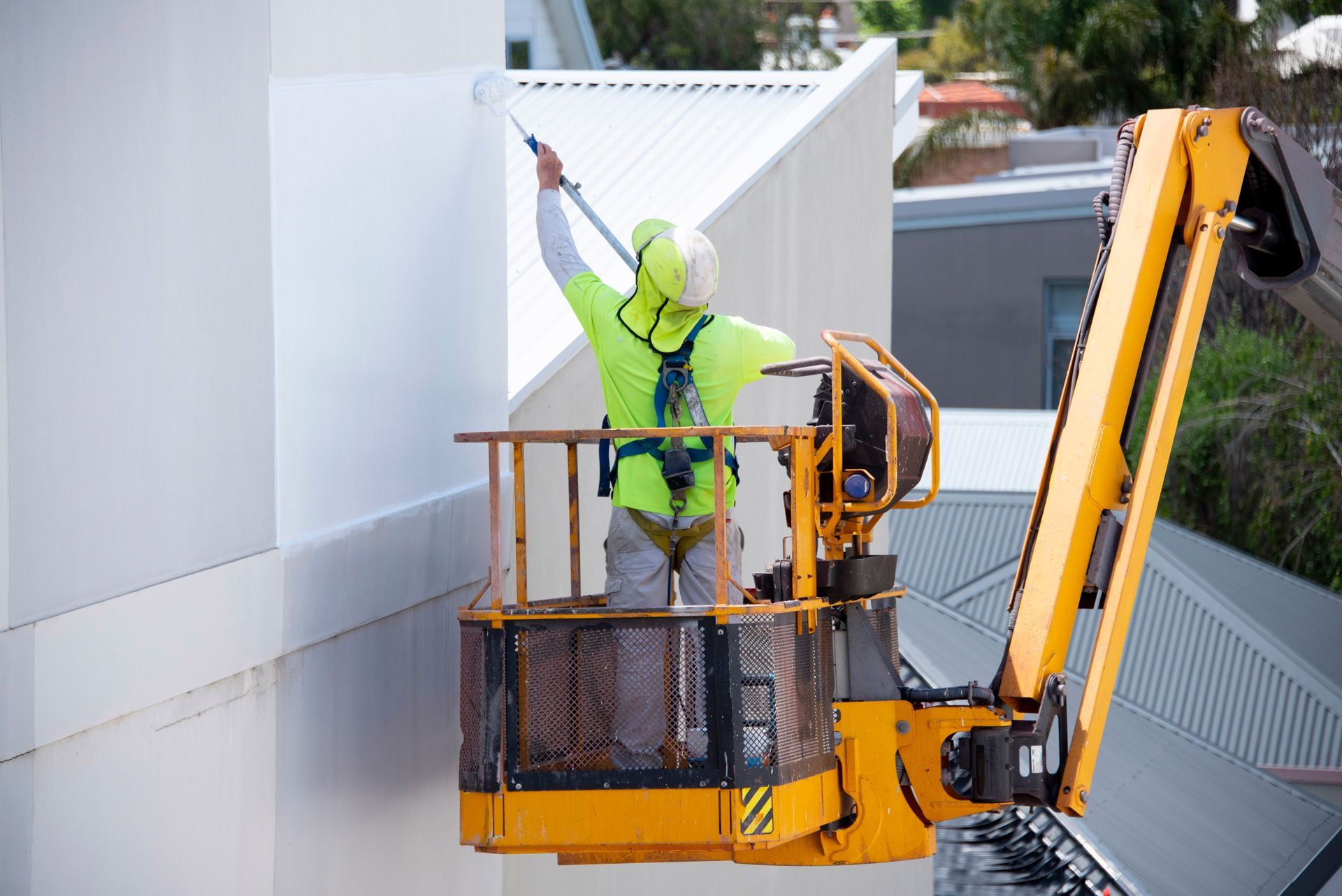 A man is painting a building from a crane