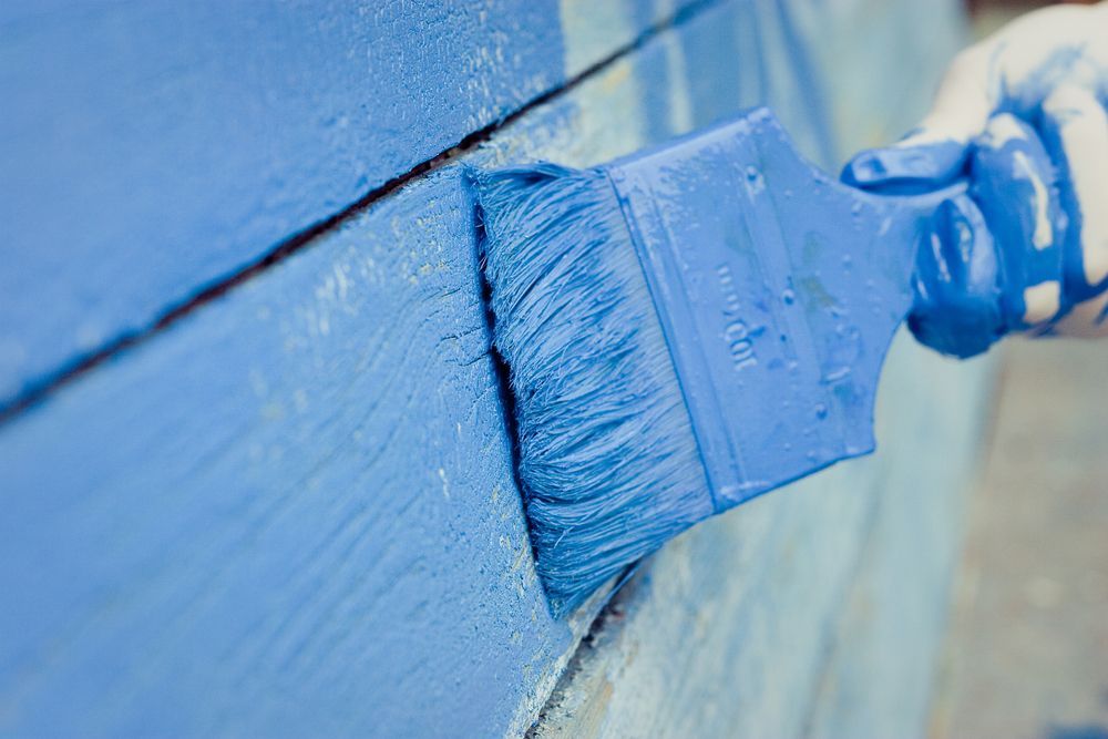 A person is painting a wall with a blue brush