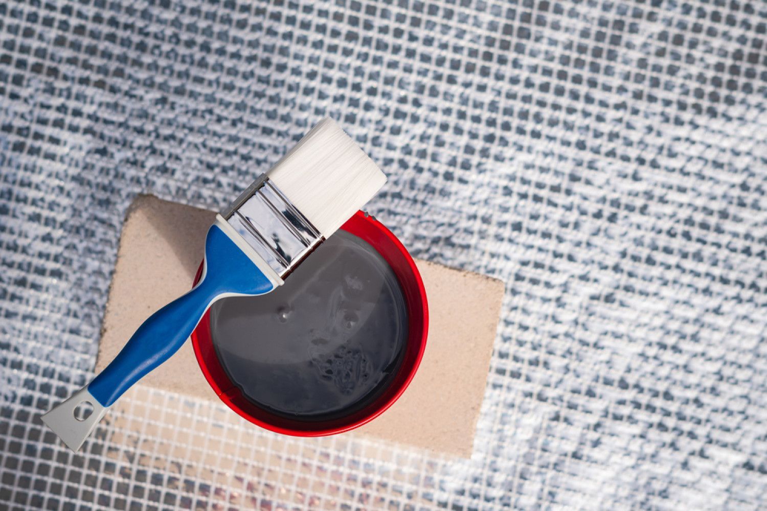 A brush is sitting on top of a bowl of paint