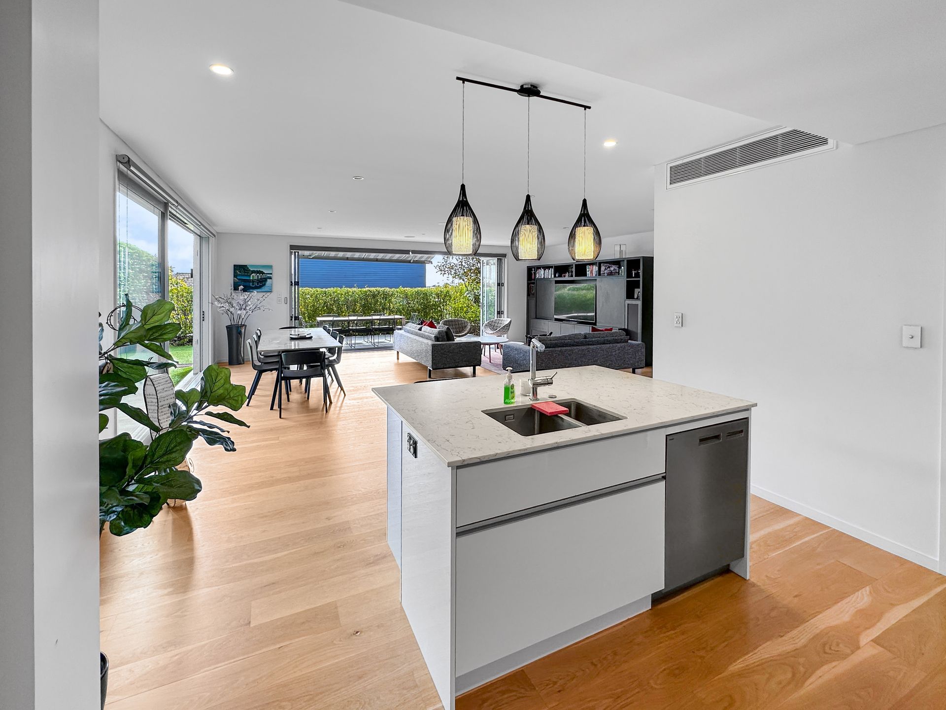 Modern kitchen with island, dining area, and living room opening onto a patio.