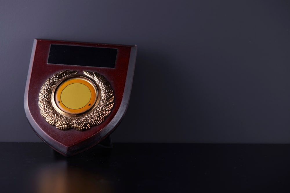 Wooden Shield With A Gold Medal On A Table — Accolades Awards Hunter Valley In Maitland, NSW