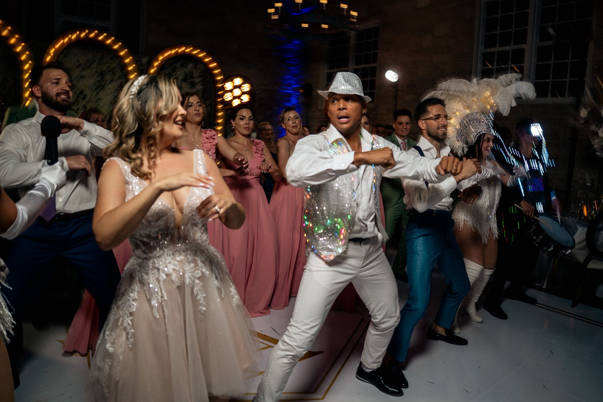 A bride and groom are dancing with a group of people at a wedding reception.