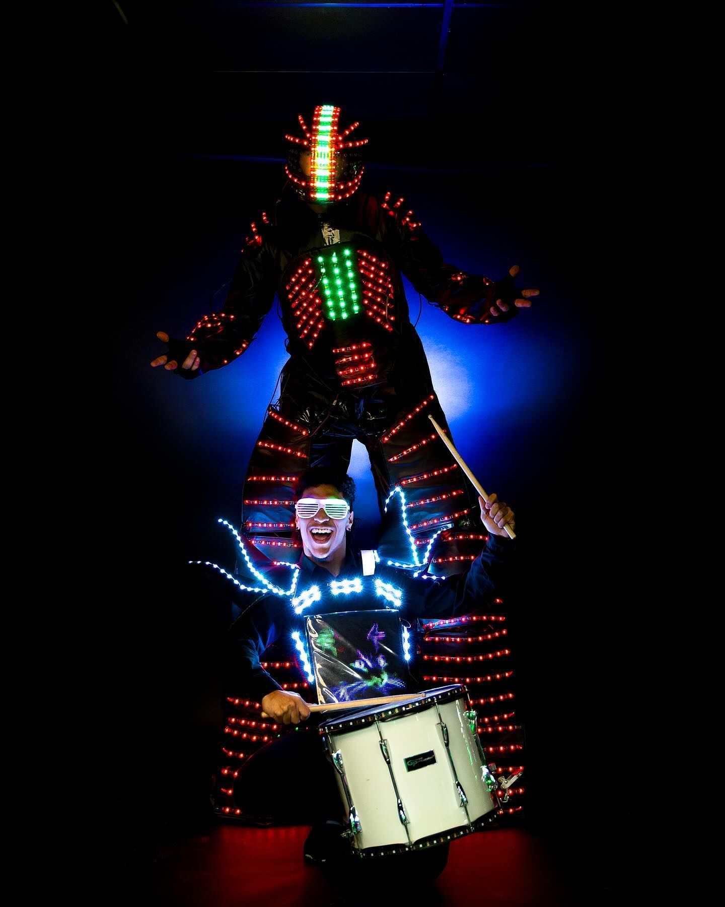 A man in a robot costume is playing a drum