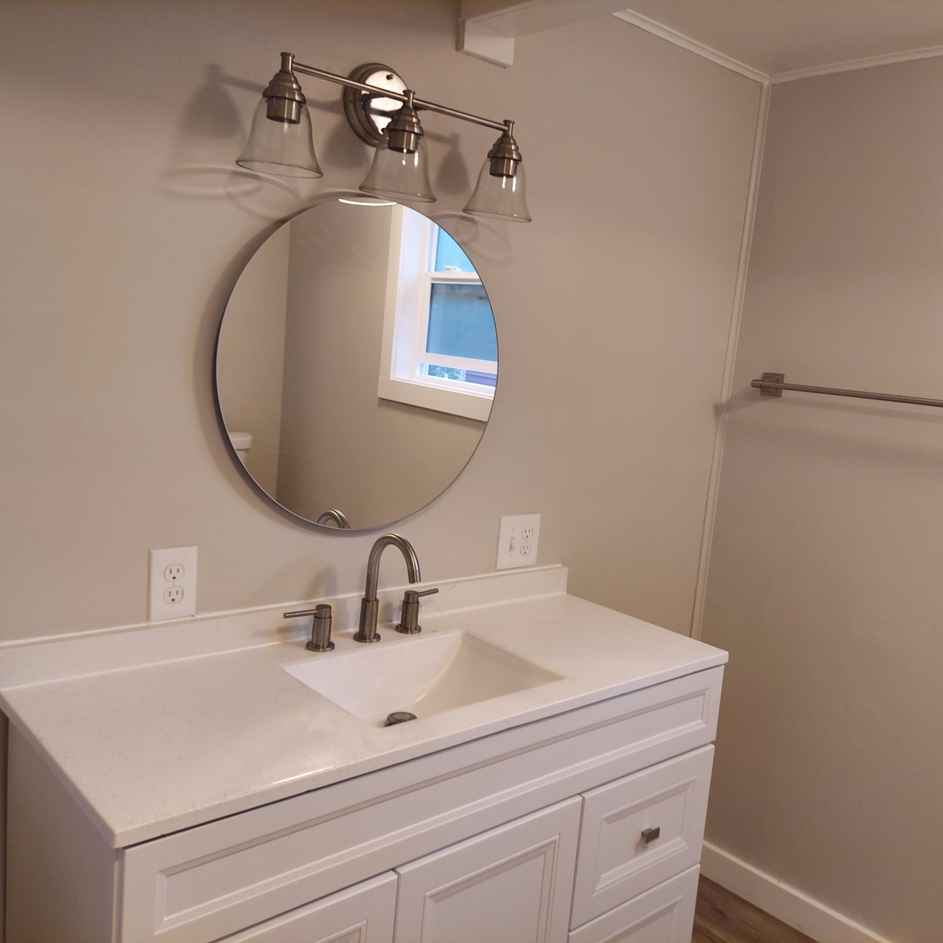 A bathroom sink with a round mirror above it