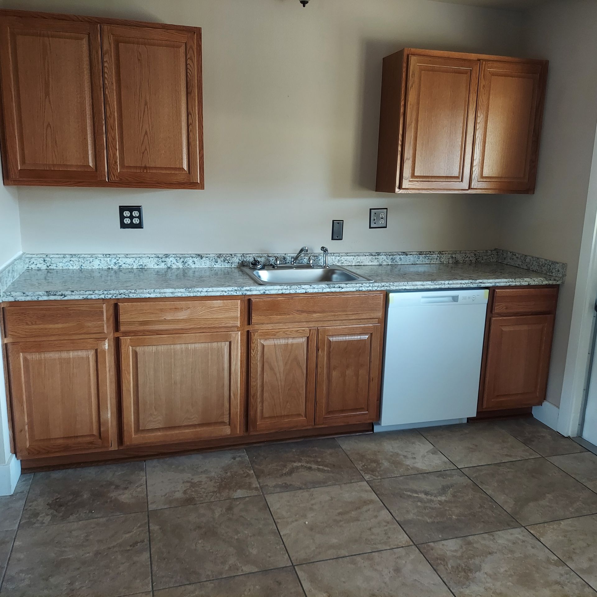 A kitchen with wooden cabinets and a white dishwasher