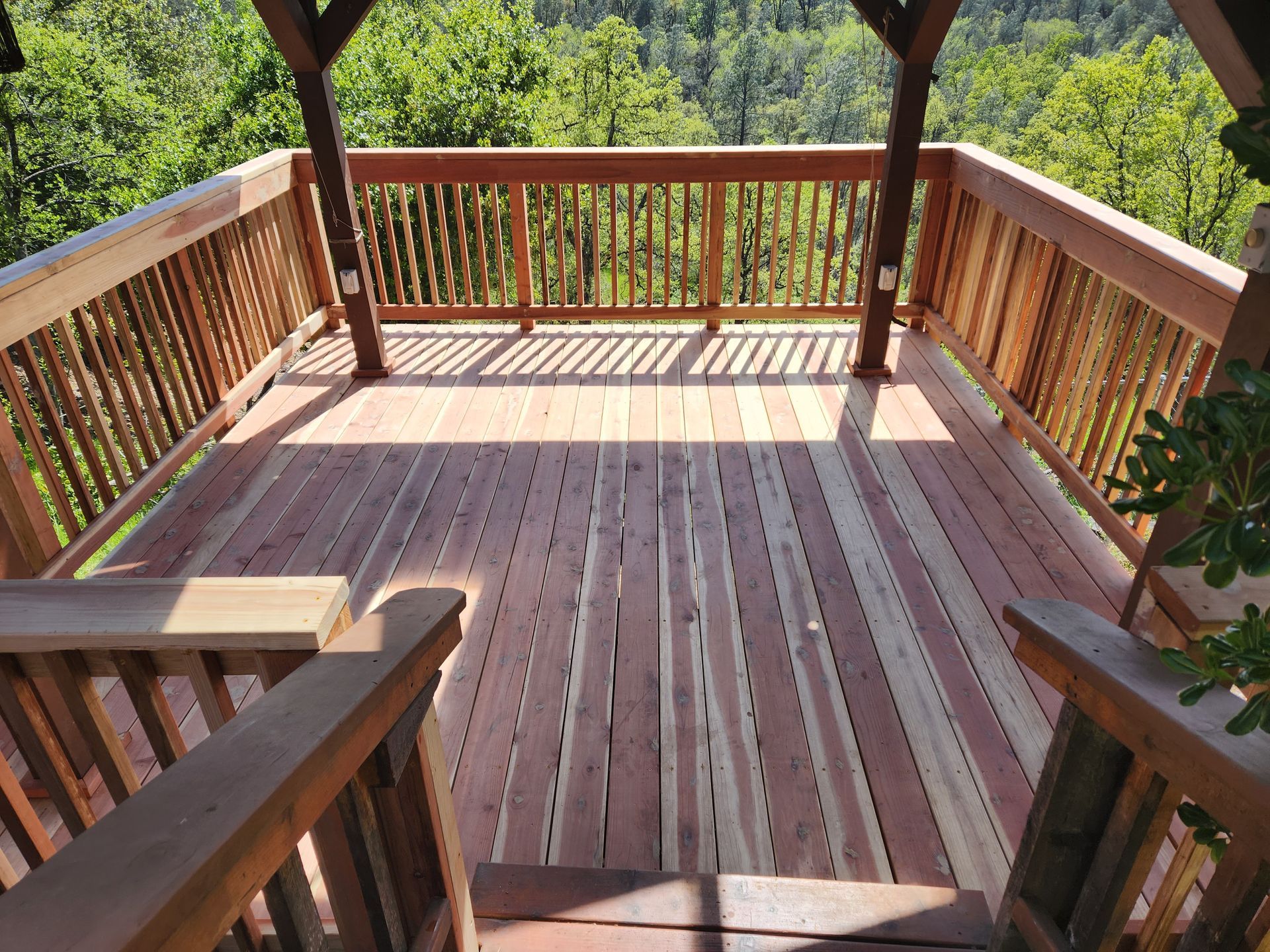 A wooden deck with a railing overlooking a forest