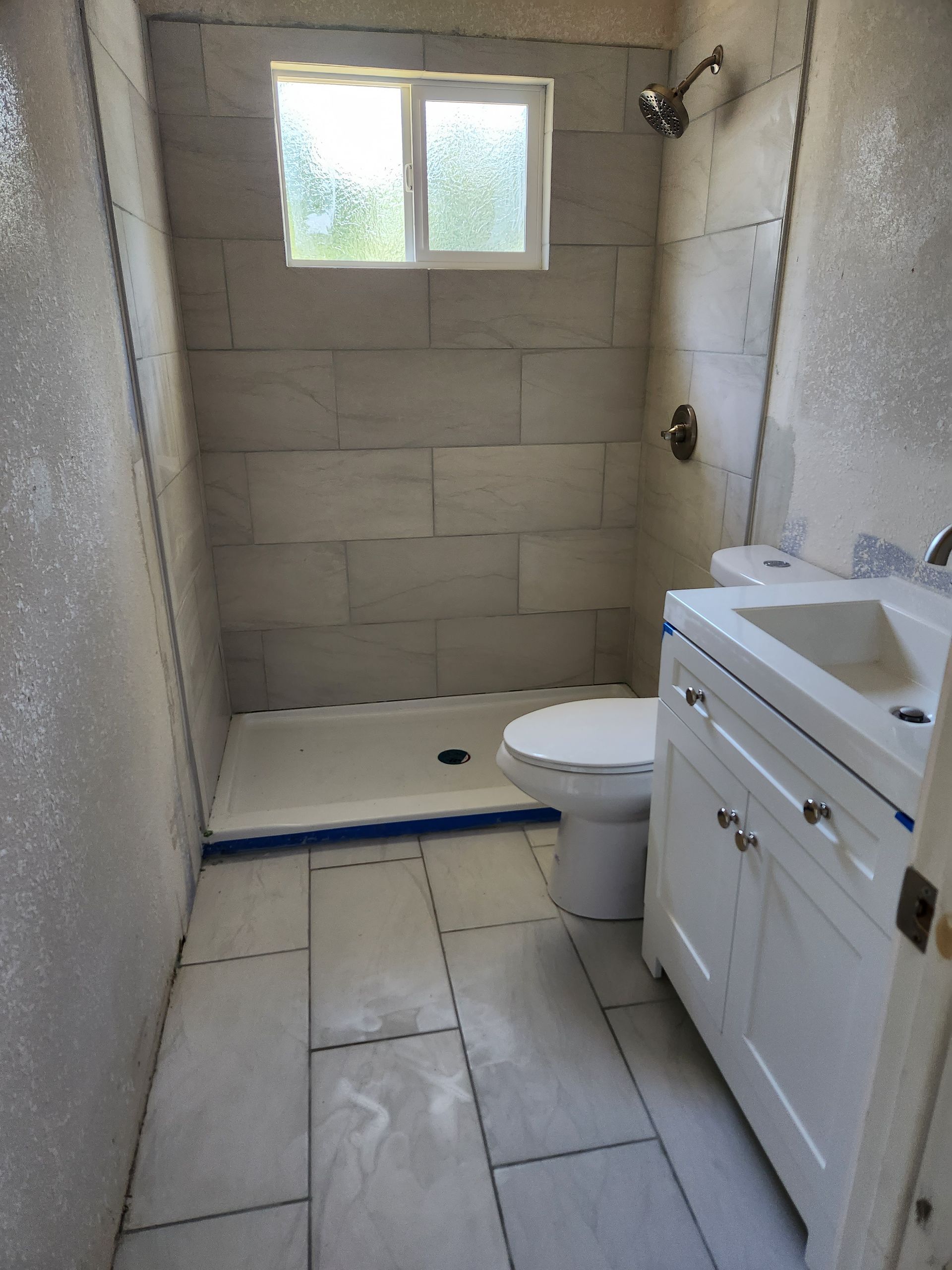 A bathroom with a toilet , sink and shower.
