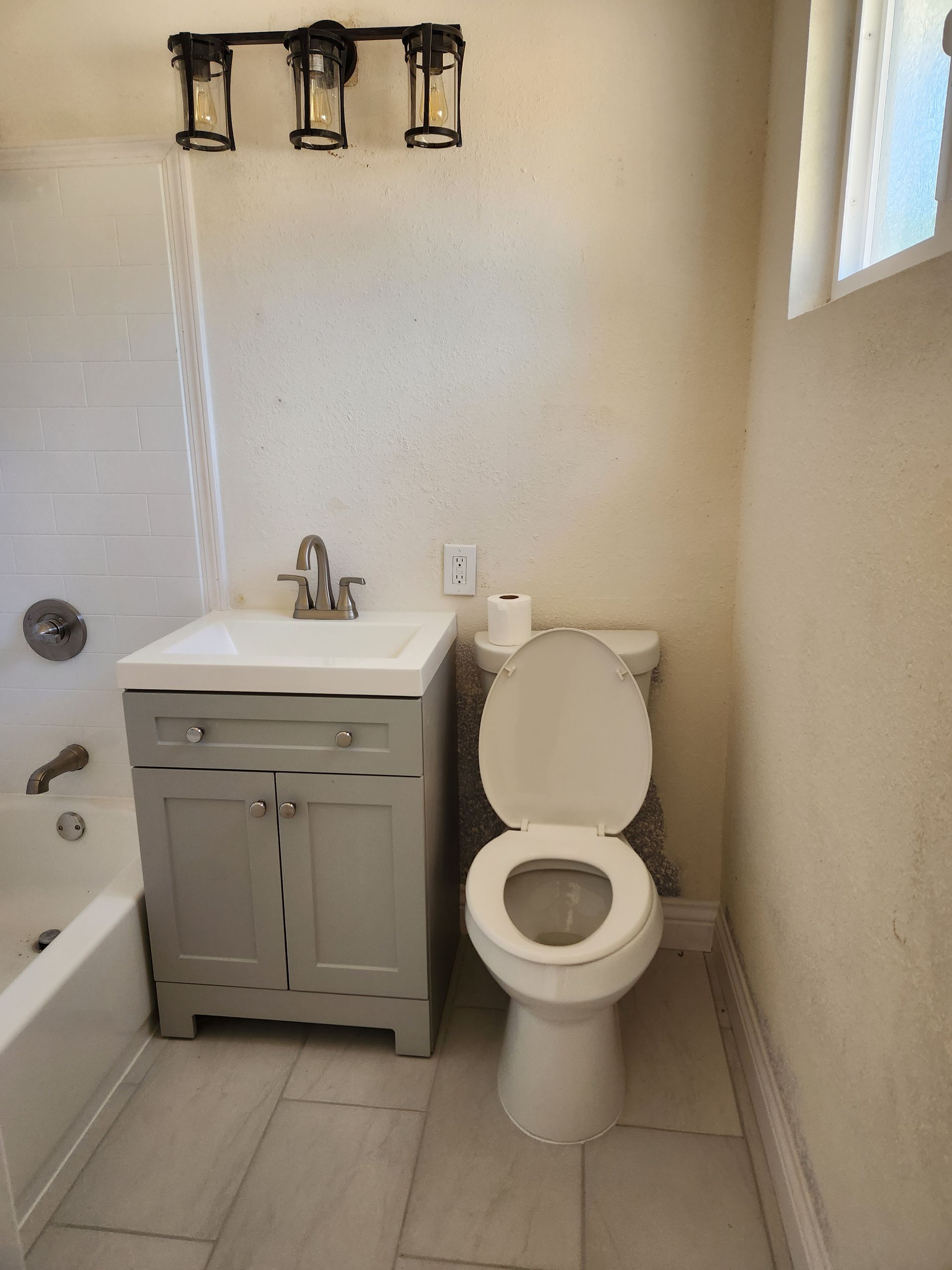 A bathroom with a toilet , sink and bathtub.