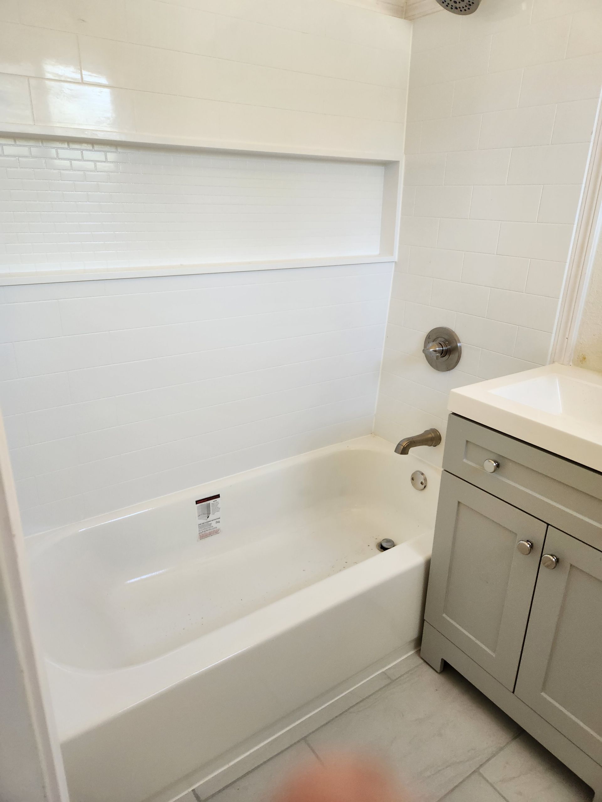 A bathroom with a bathtub , sink , and window.