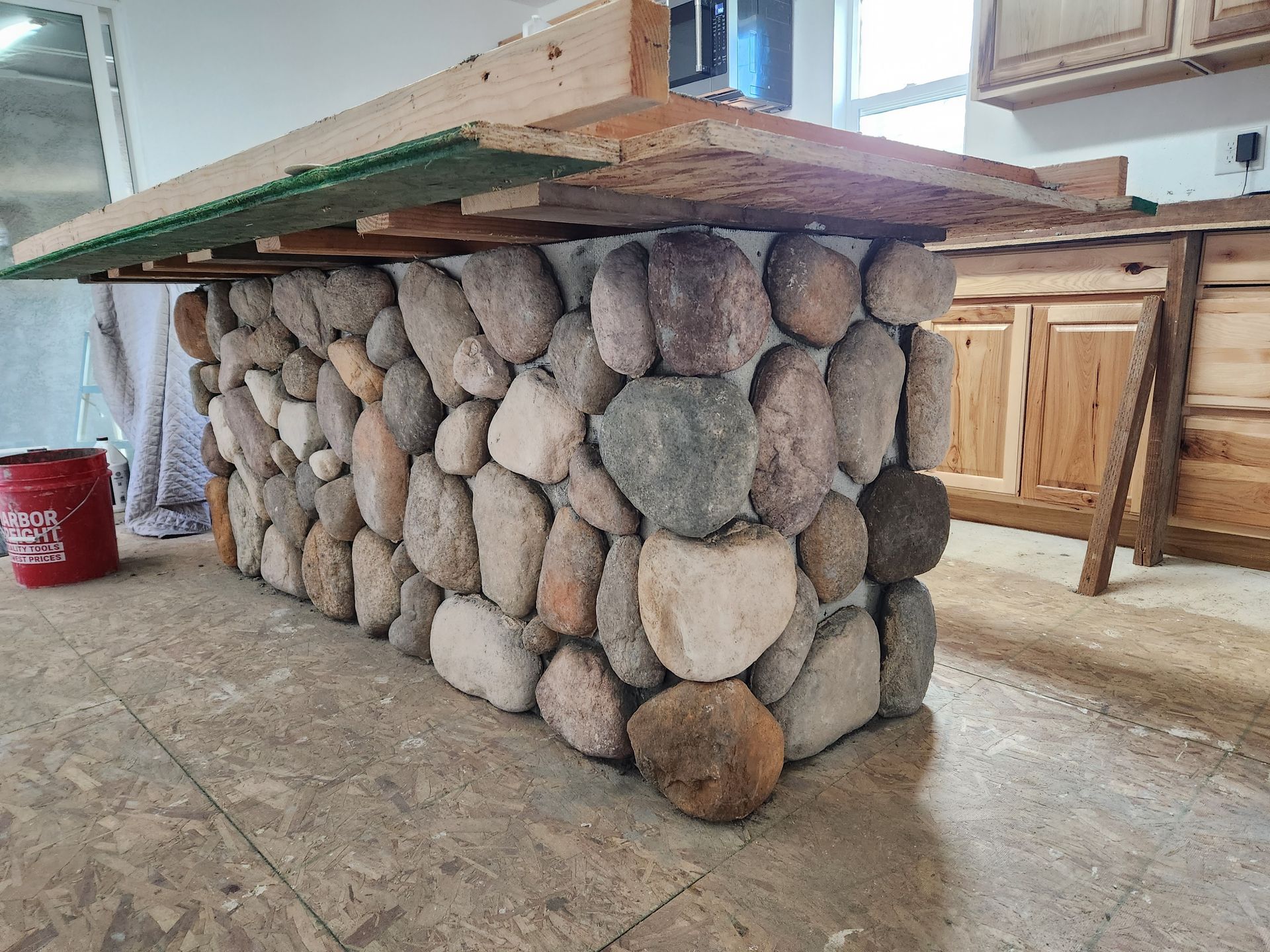 A table made of rocks and wood is being built in a kitchen.