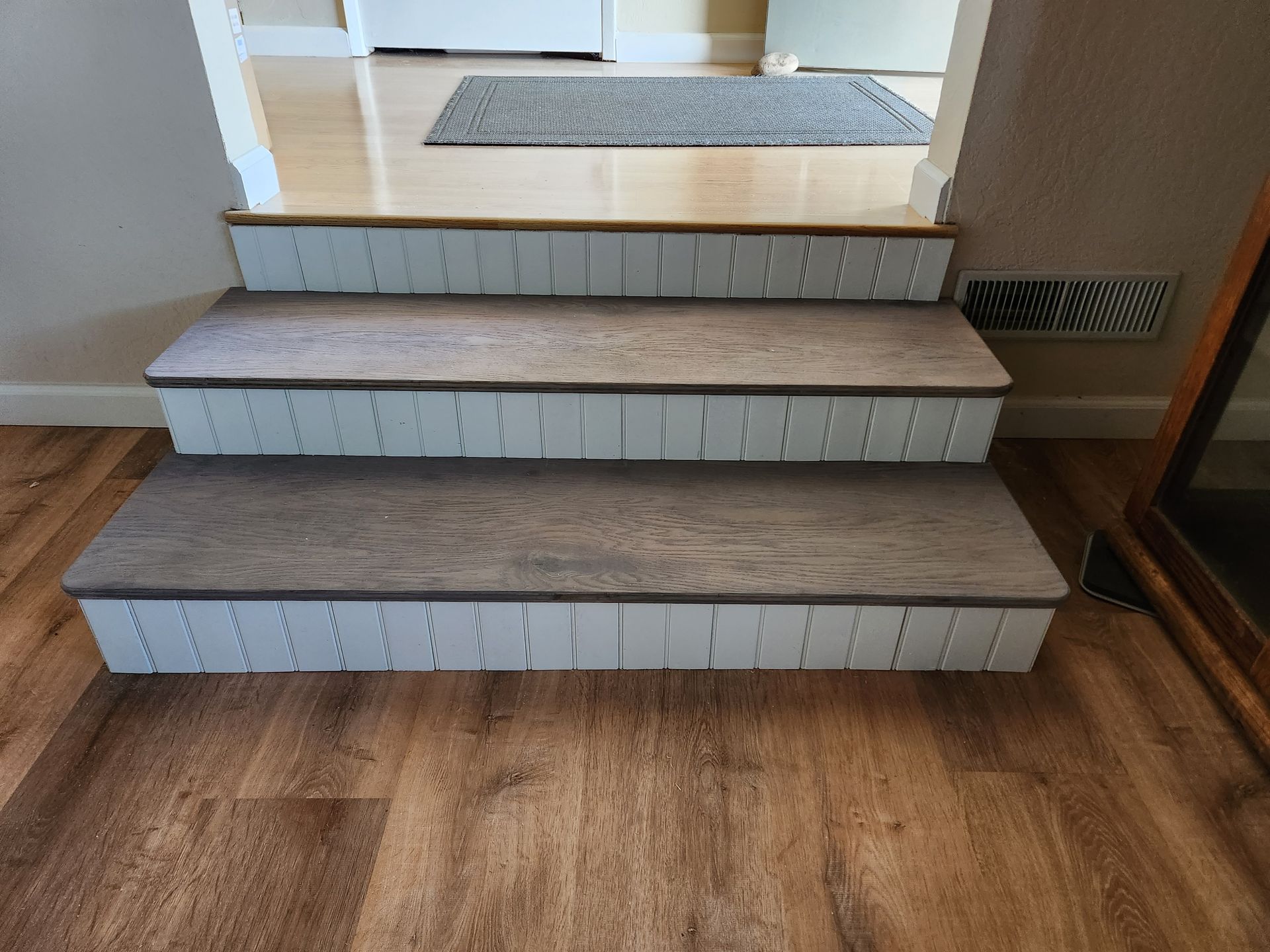 A set of stairs with a wooden floor in a living room.