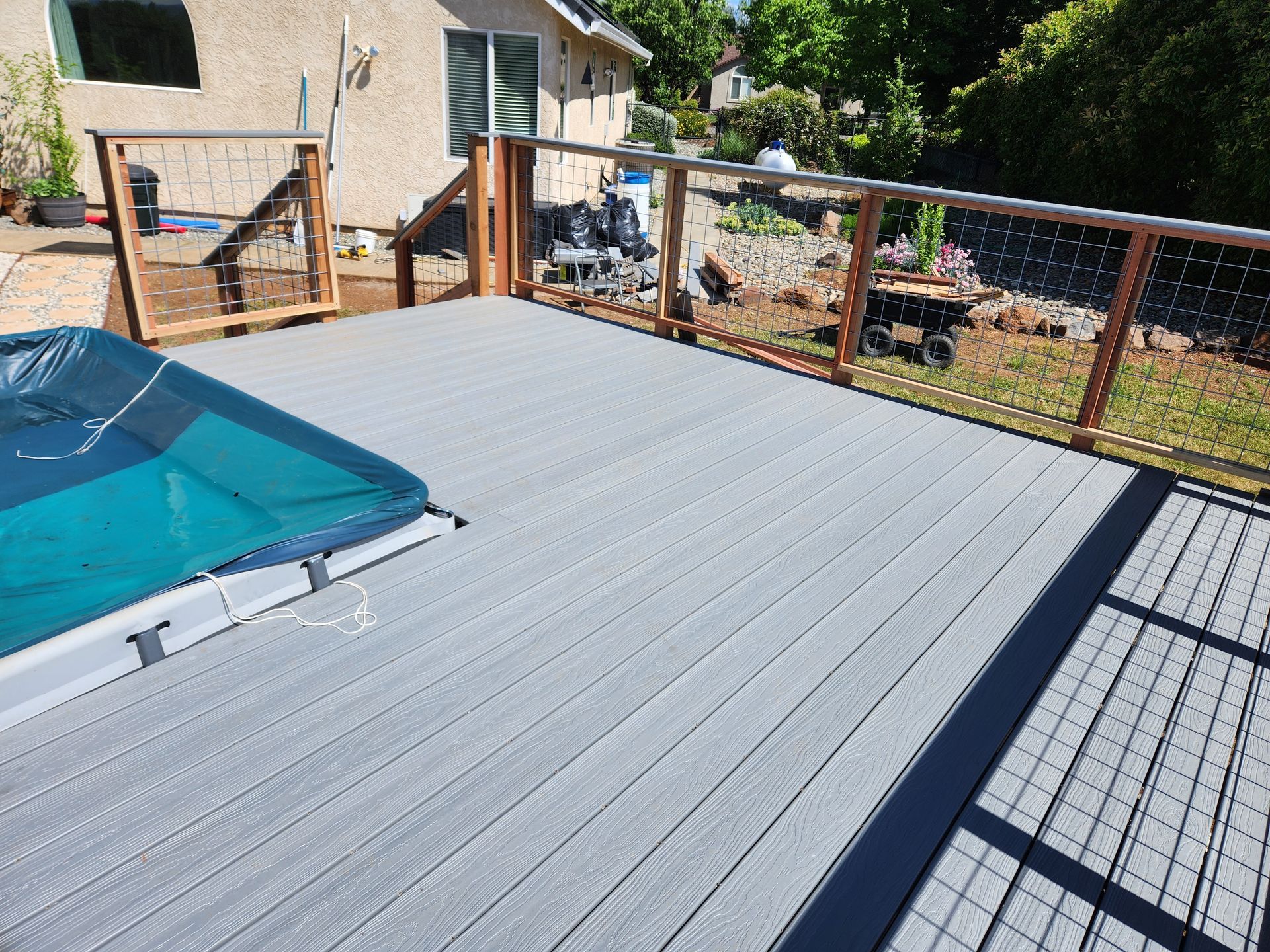 A deck with a hot tub on it and a house in the background