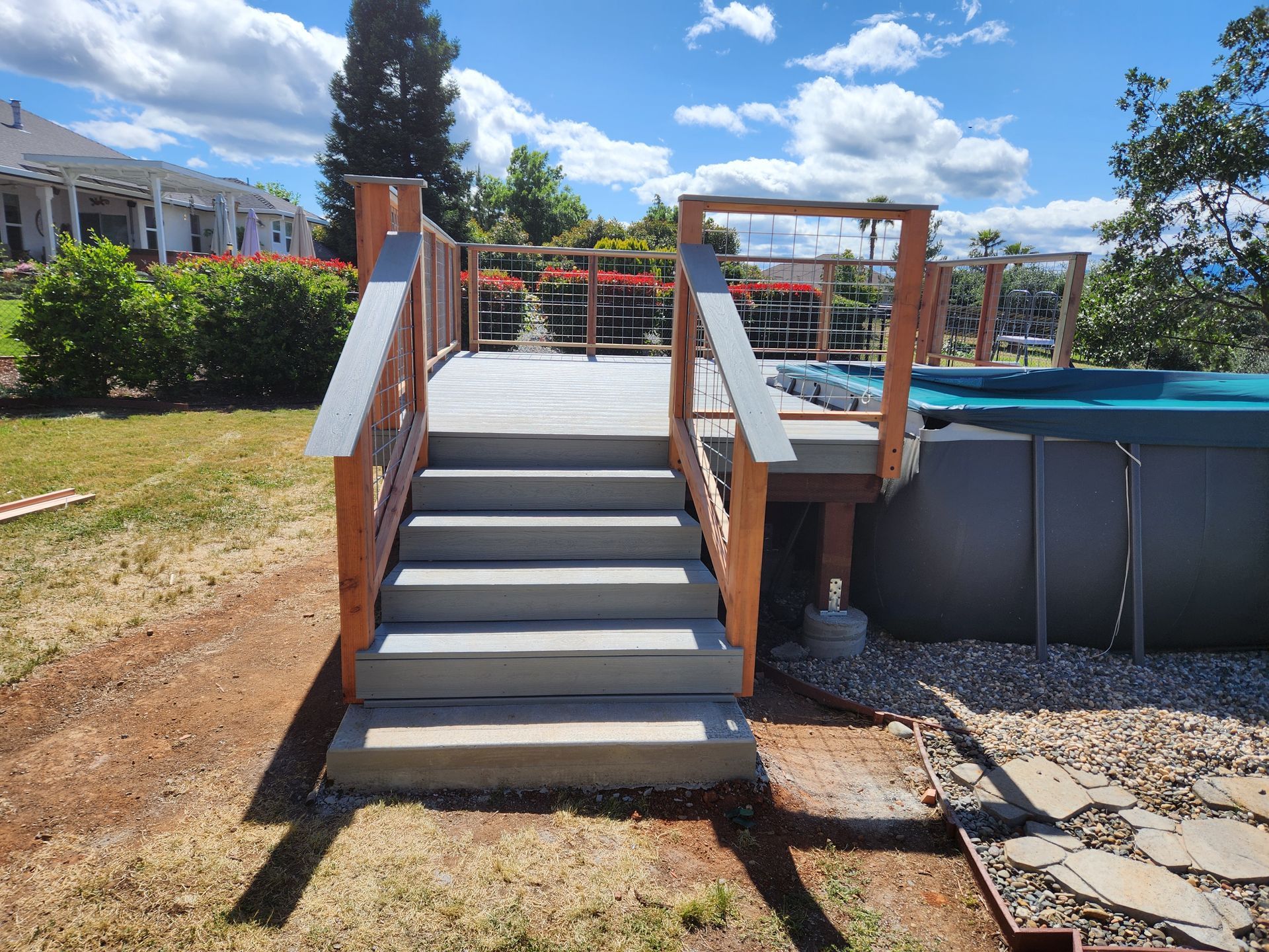A deck with stairs leading up to it next to a pool.