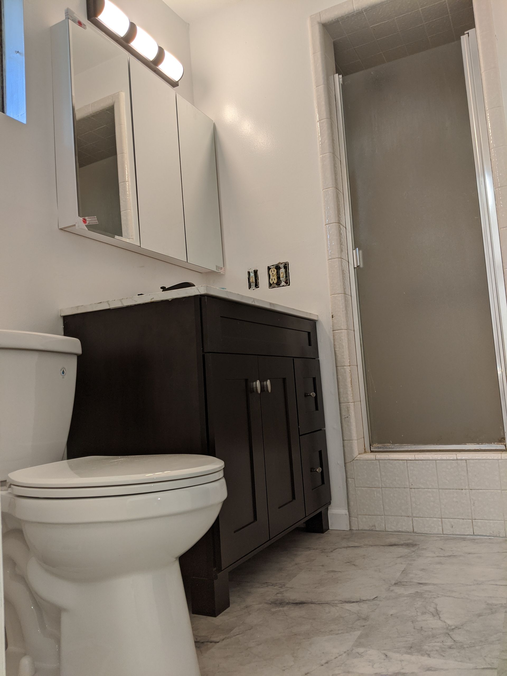 A bathroom with a toilet a sink and a mirror