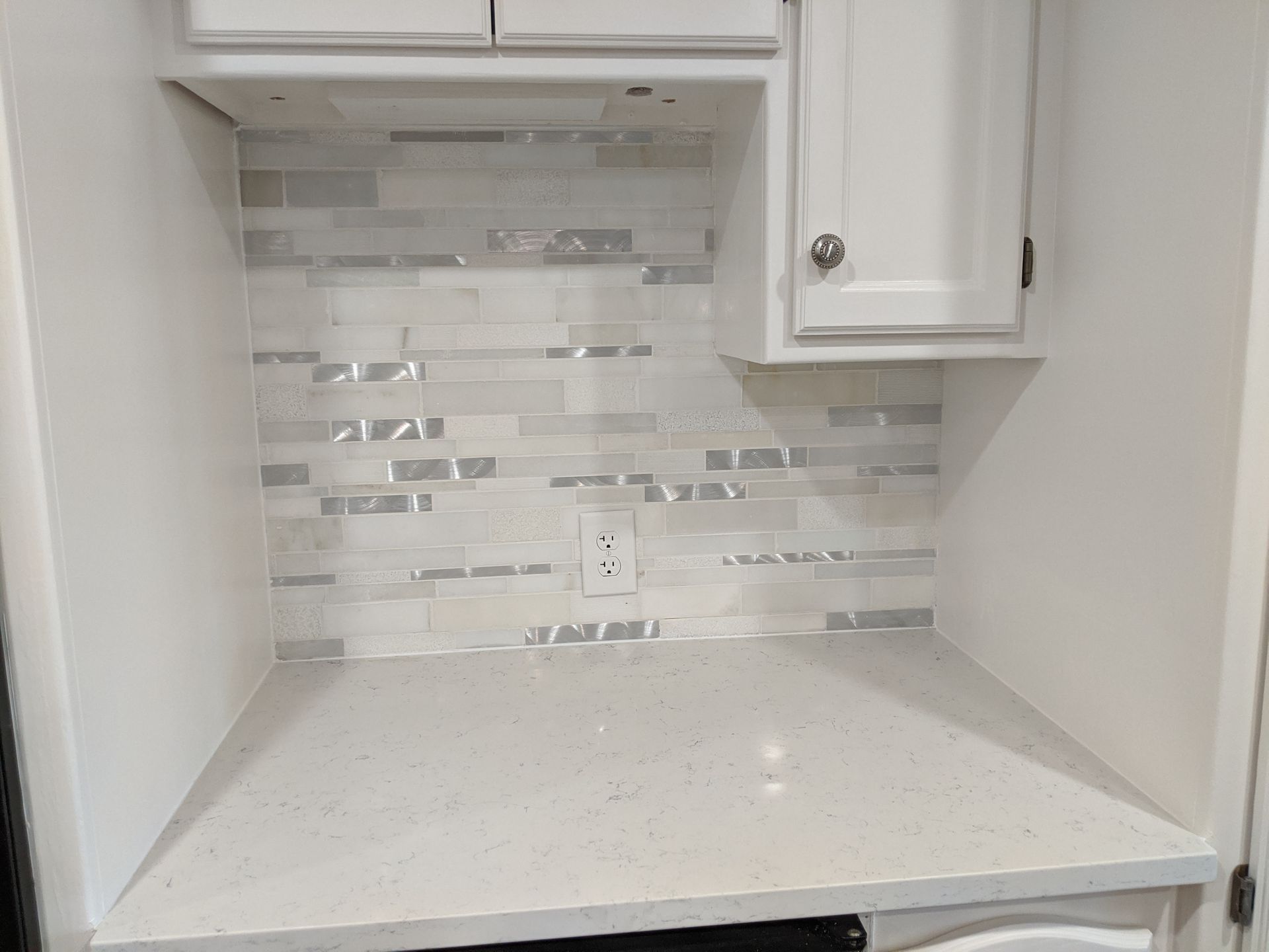 A kitchen with white cabinets and a white counter top.