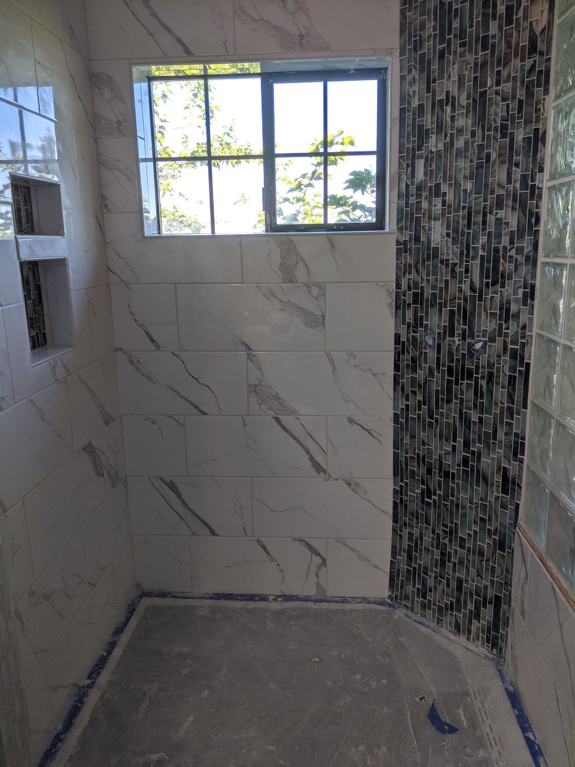 A bathroom with marble tiles and a window