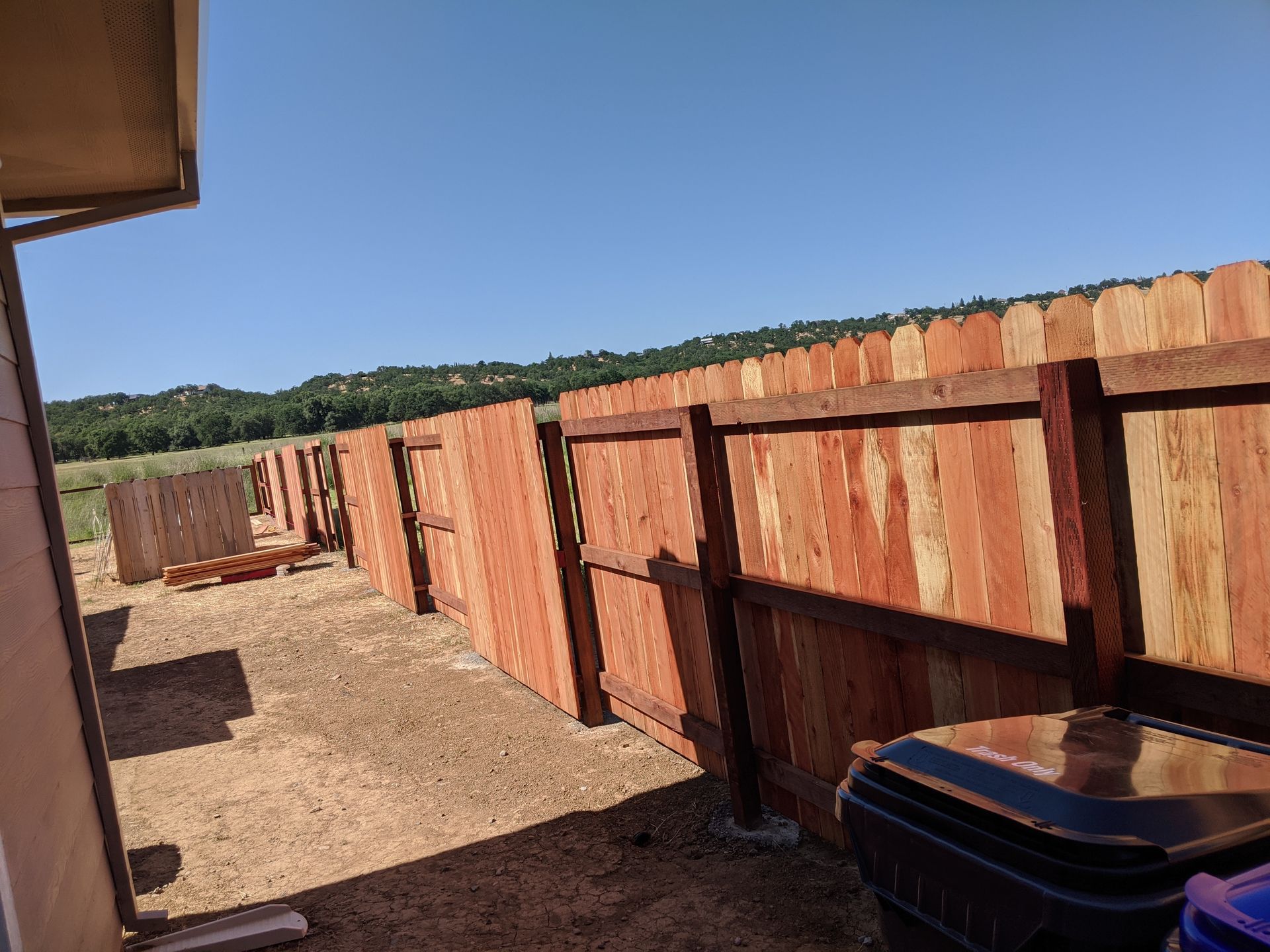 A wooden fence is being built in a backyard.