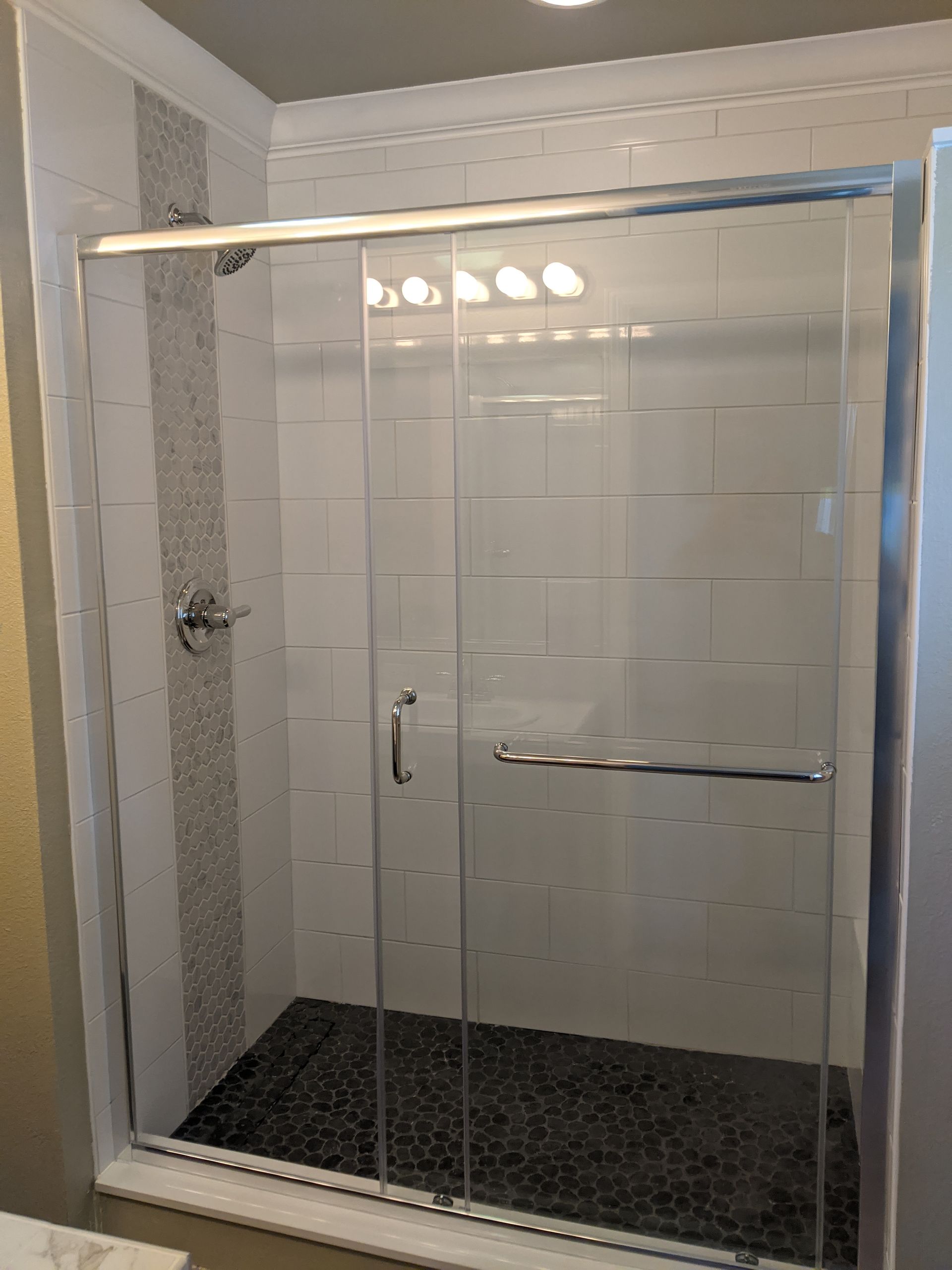A bathroom with a sliding glass shower door.