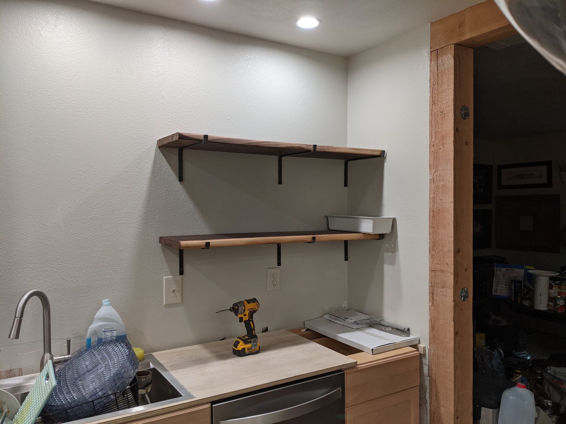 A kitchen with a sink , dishwasher , and shelves.