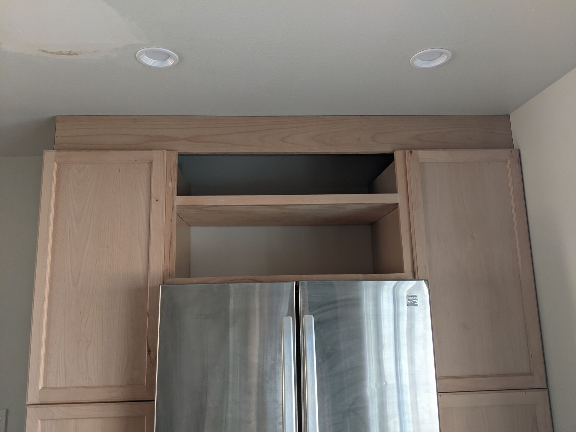 A stainless steel refrigerator in a kitchen with wooden cabinets