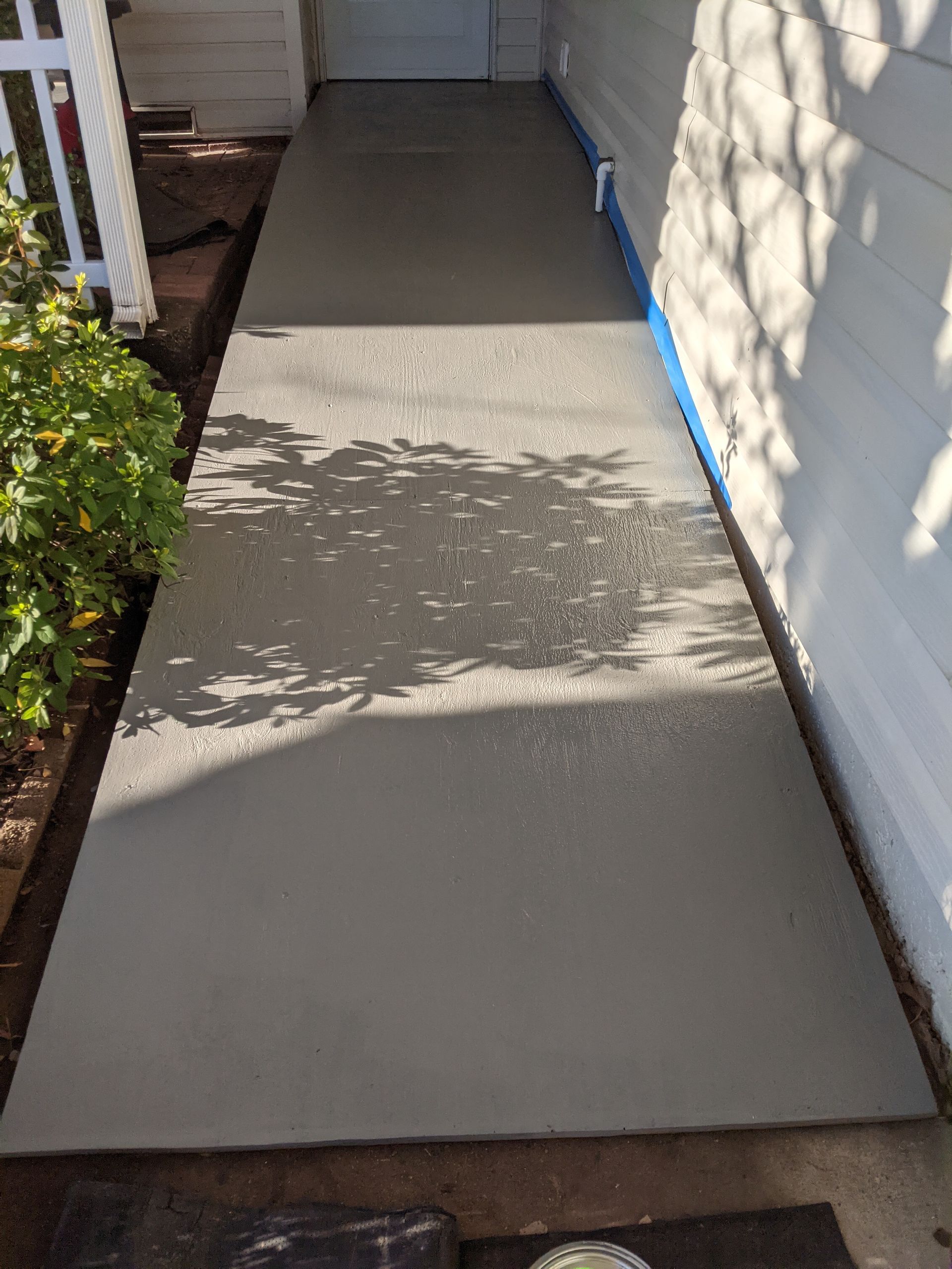 A concrete walkway leading to the front door of a house.