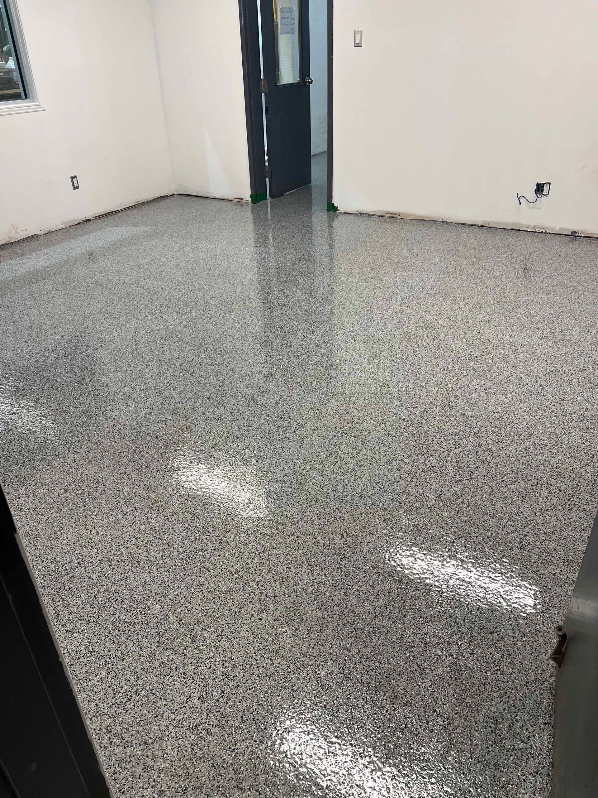 Pièce avec un sol en époxy gris récemment installé, qui reflète la lumière.