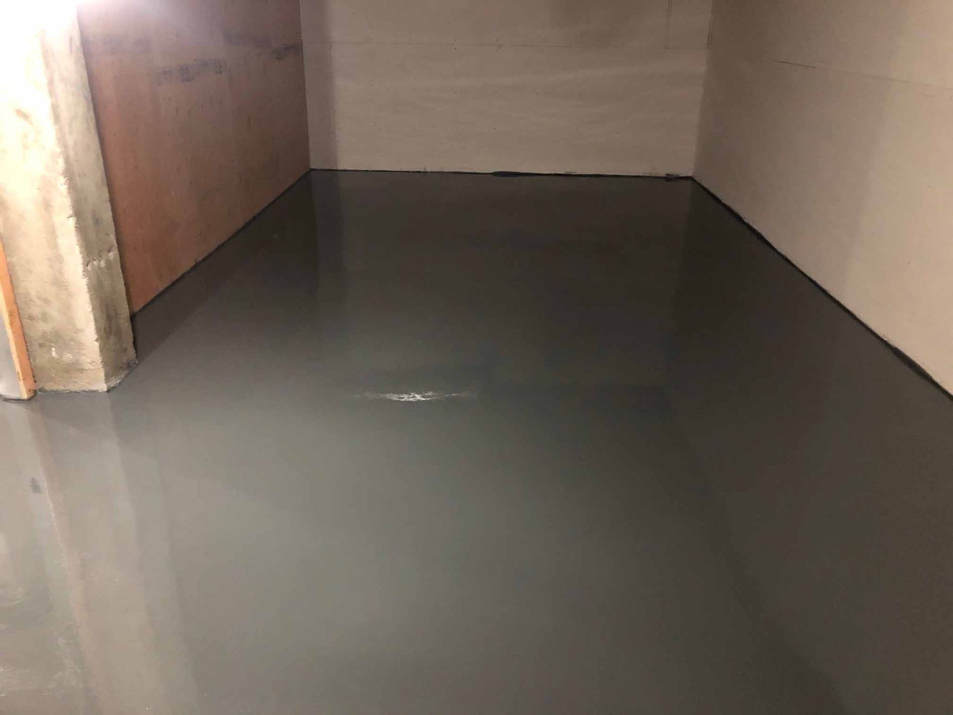 Un sol en époxy gris dans une pièce vide, reflétant les murs environnants.