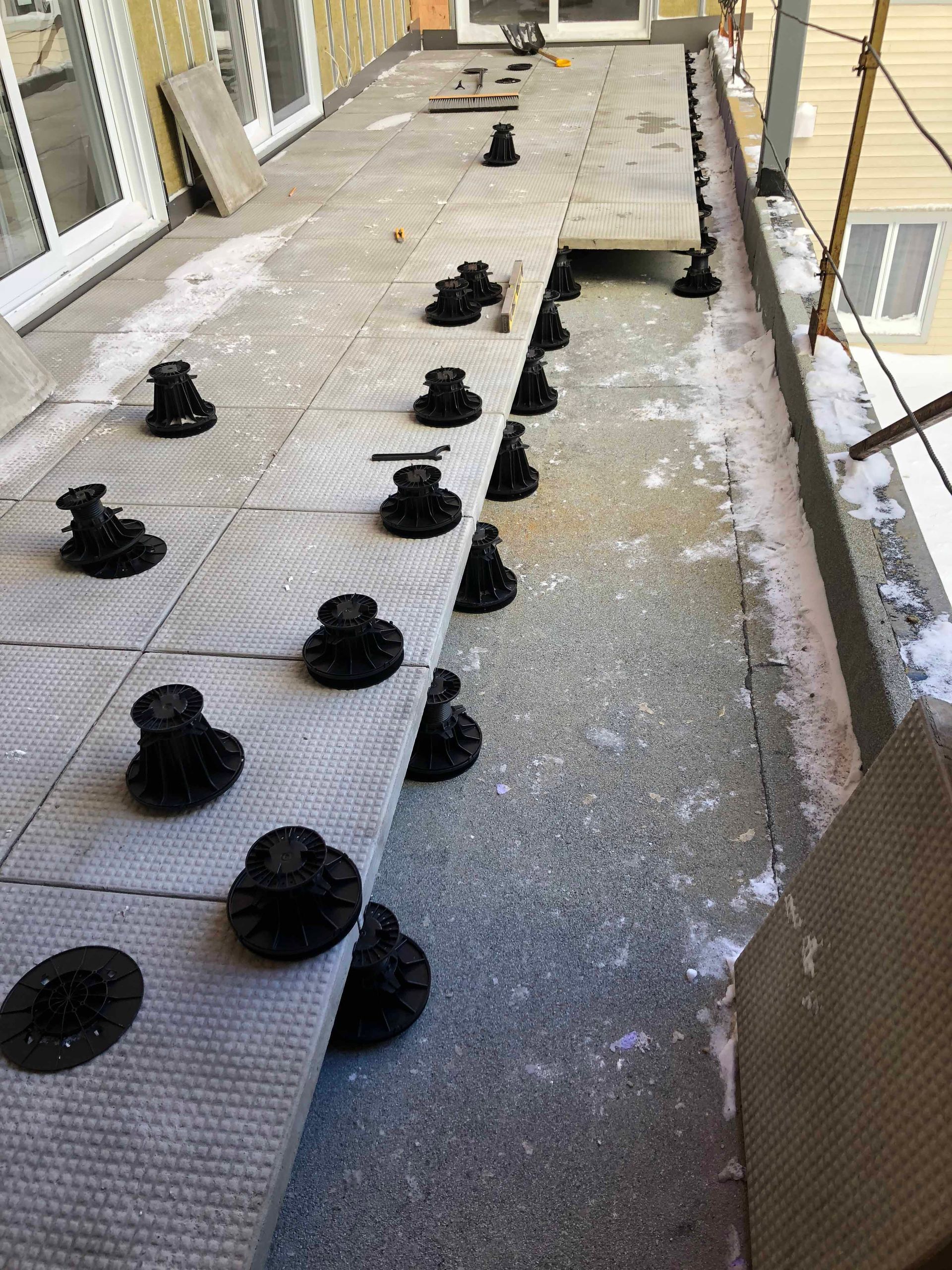 Pose de carreaux sur des supports réglables sur une surface extérieure, éventuellement un balcon.