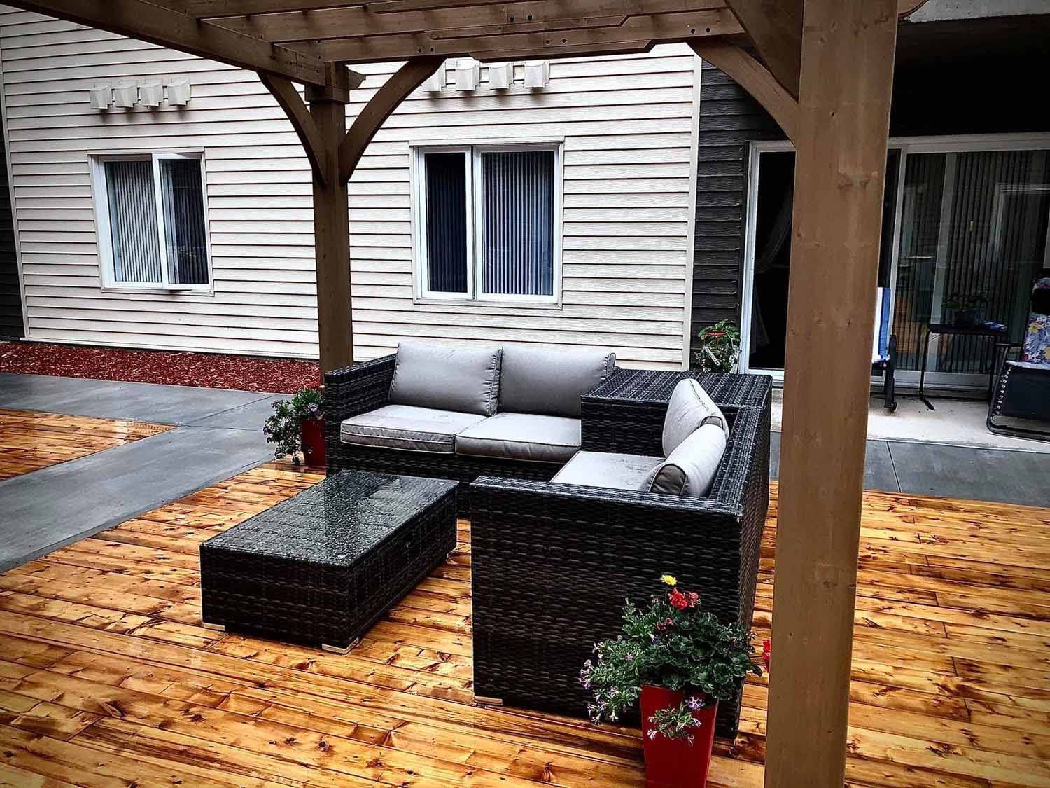 Terrasse extérieure avec mobilier en osier, sous une pergola en bois.
