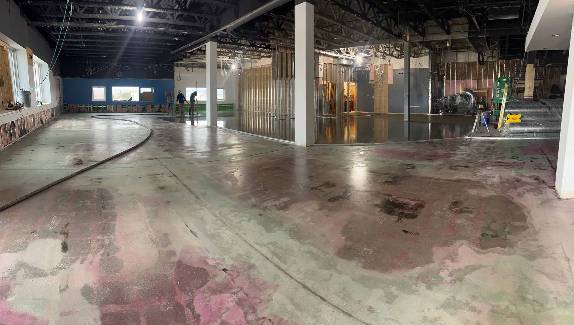 Intérieur d'un espace commercial inondé ; sol mouillé, murs apparents, travaux de construction.