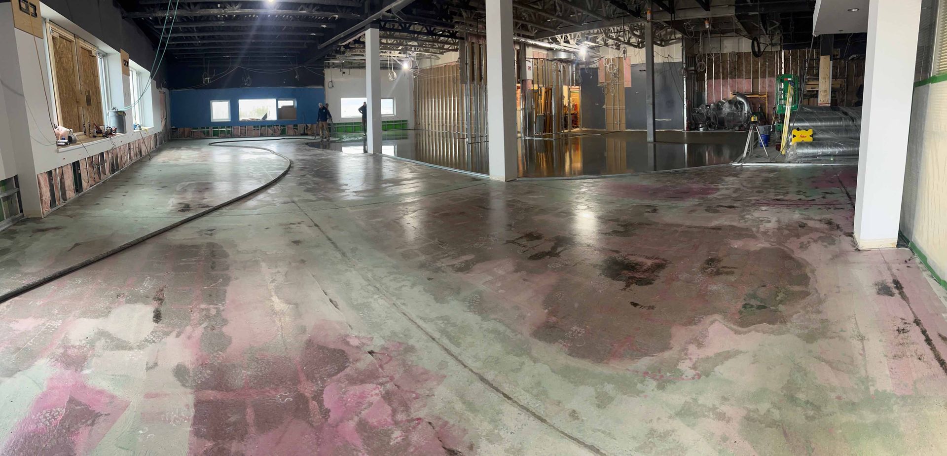 Espace intérieur en travaux, sol en béton brut, murs partiellement démolis.