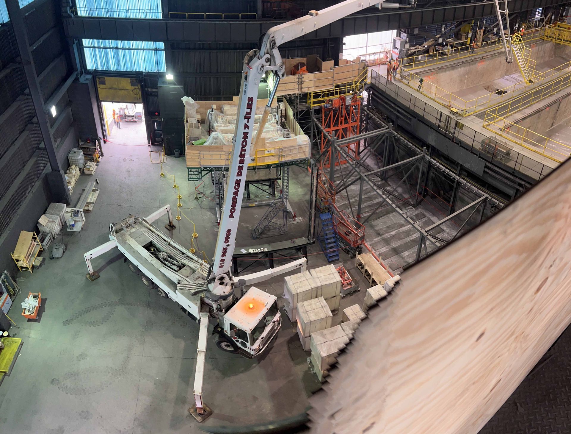 Camion-pompe à béton déversant du béton sur un chantier à l'intérieur d'un grand bâtiment.