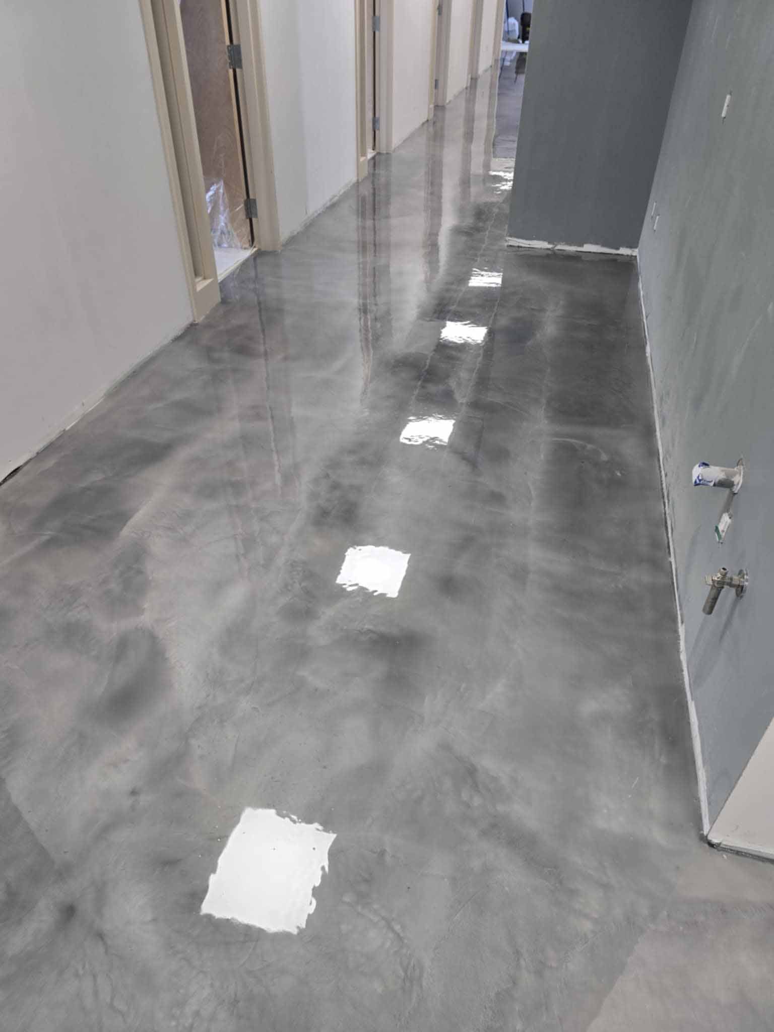Sol en époxy gris dans un couloir avec spots encastrés et portes.