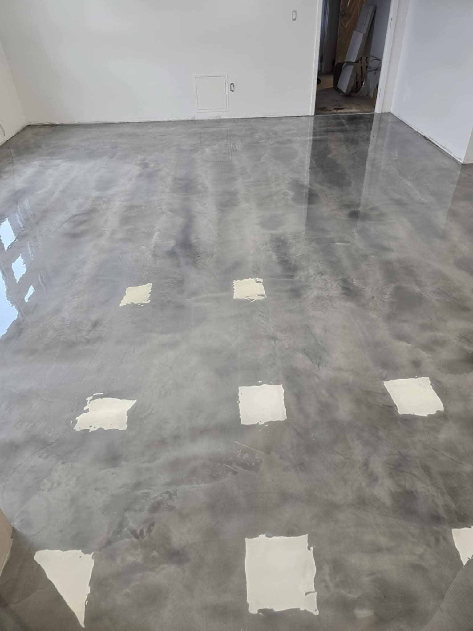 Sol en époxy gris brillant avec des carrés blancs éclatants dans une pièce.