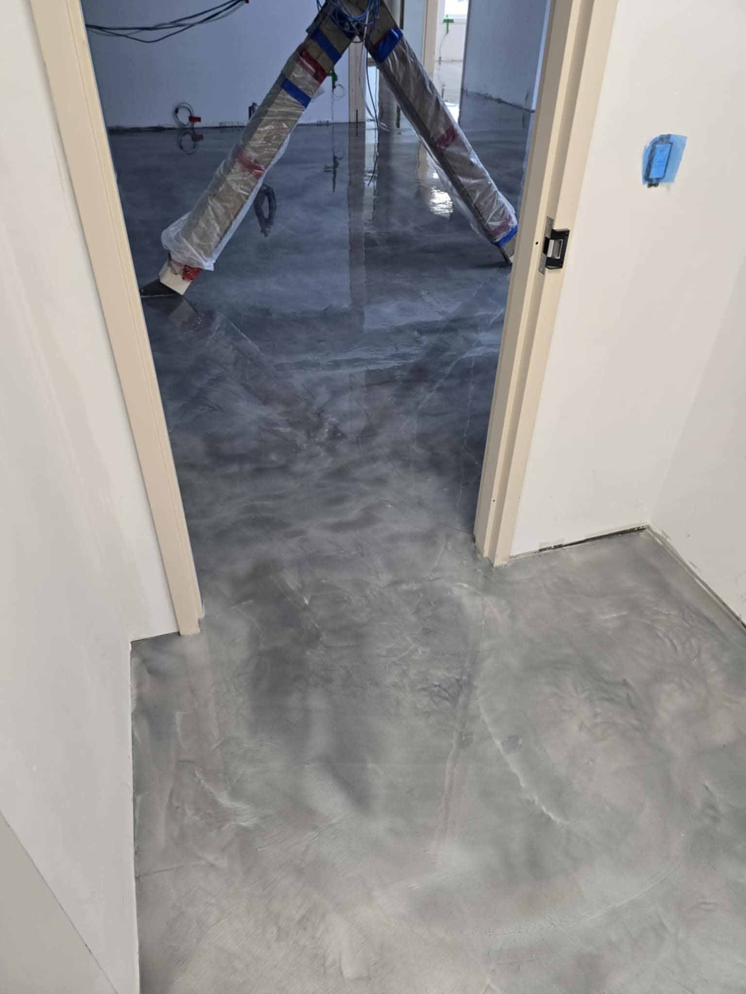 Sol en époxy gris métallisé dans un couloir avec une porte ouverte donnant sur une autre pièce.