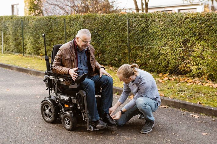 A man in a wheelchair is being helped by a woman.