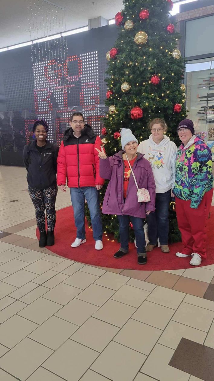 A pensioner on a wheelchair and his adult son are walking around the park.