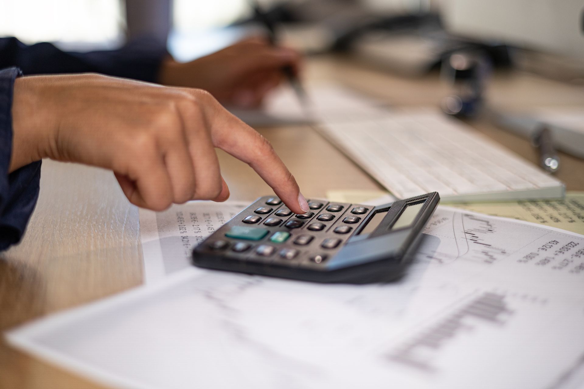 Close up woman hand typing on a calculator, doing accounting services at The Acct & Tax Co. in Harbo