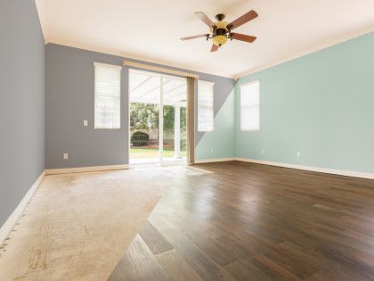 An empty living room with hardwood floors and a ceiling fan.
