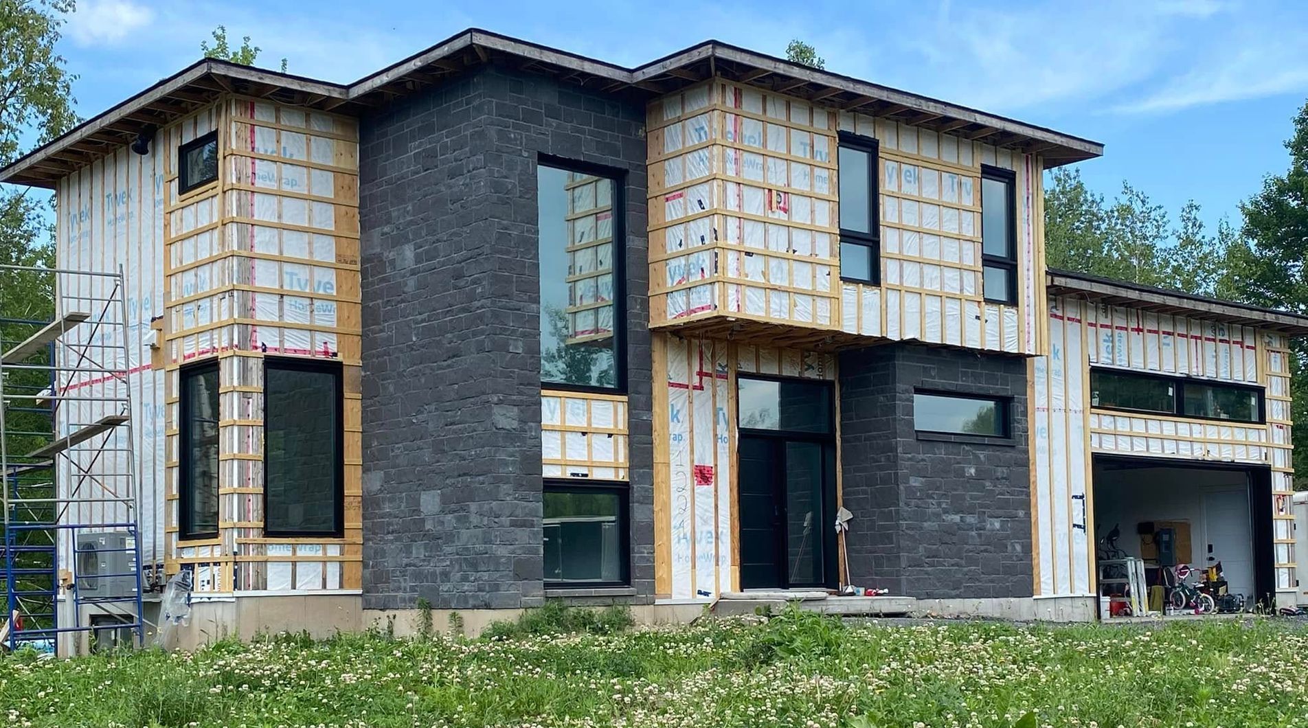 Une grande maison est en construction dans un champ herbeux.