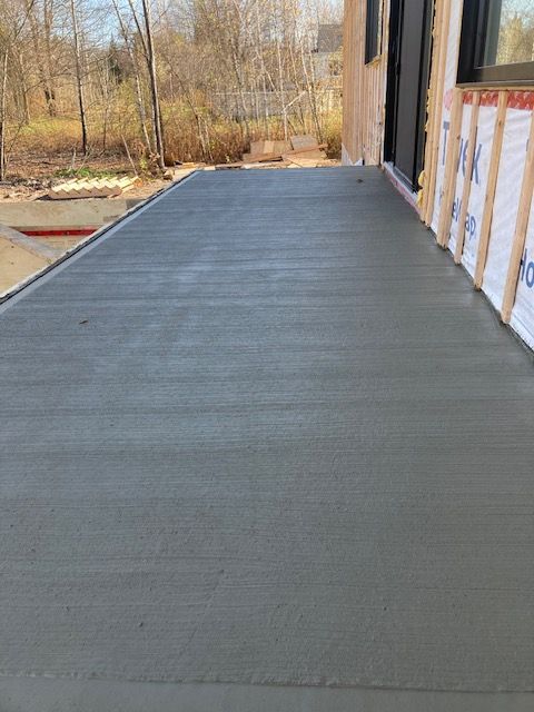 Un porche en béton est en cours de construction sur le côté d'une maison.