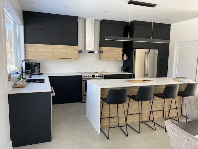 Une cuisine avec des armoires noires et des comptoirs blancs