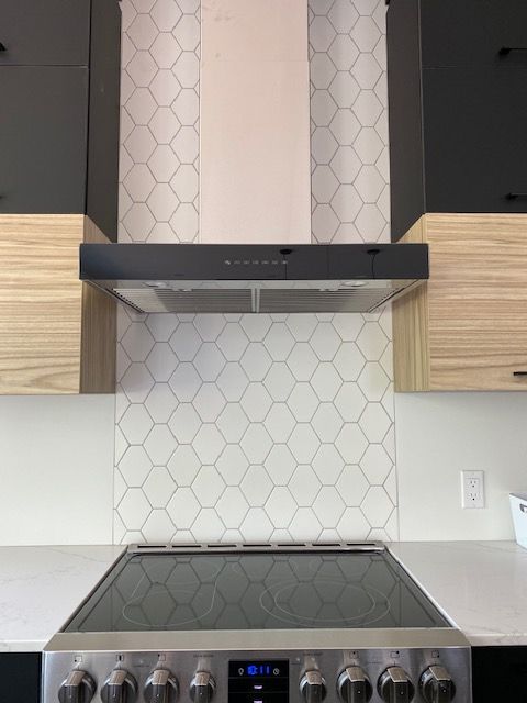 Une cuisine avec une cuisinière et une hotte au-dessus