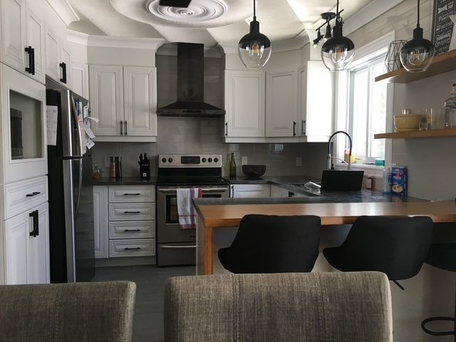 Une cuisine avec des armoires blanches et des chaises noires