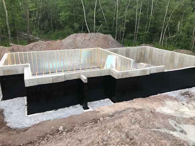 Une base en béton pour une maison est en cours de construction au milieu d'une forêt.