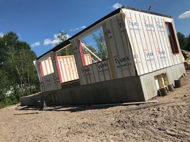 Une maison est en construction sur un terrain en terre.