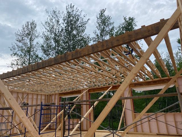 Une maison est en construction avec des poutres en bois et des échafaudages