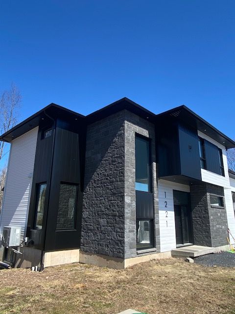Une maison en noir et blanc avec un ciel bleu en arrière-plan.