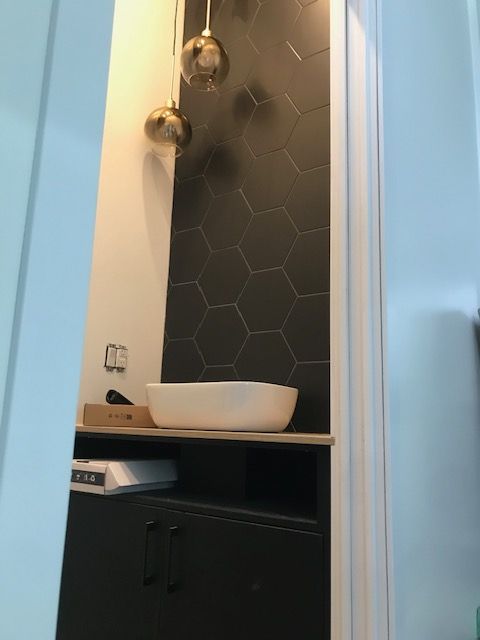 Une salle de bain avec du carrelage noir et un lavabo blanc